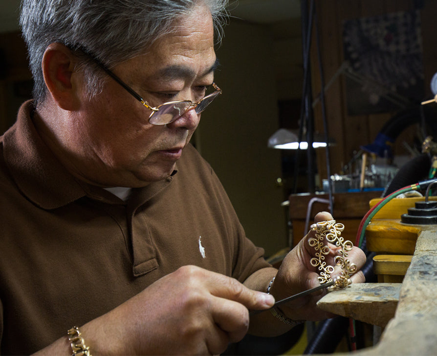 a craftsman using the tool to make the gold bracelet