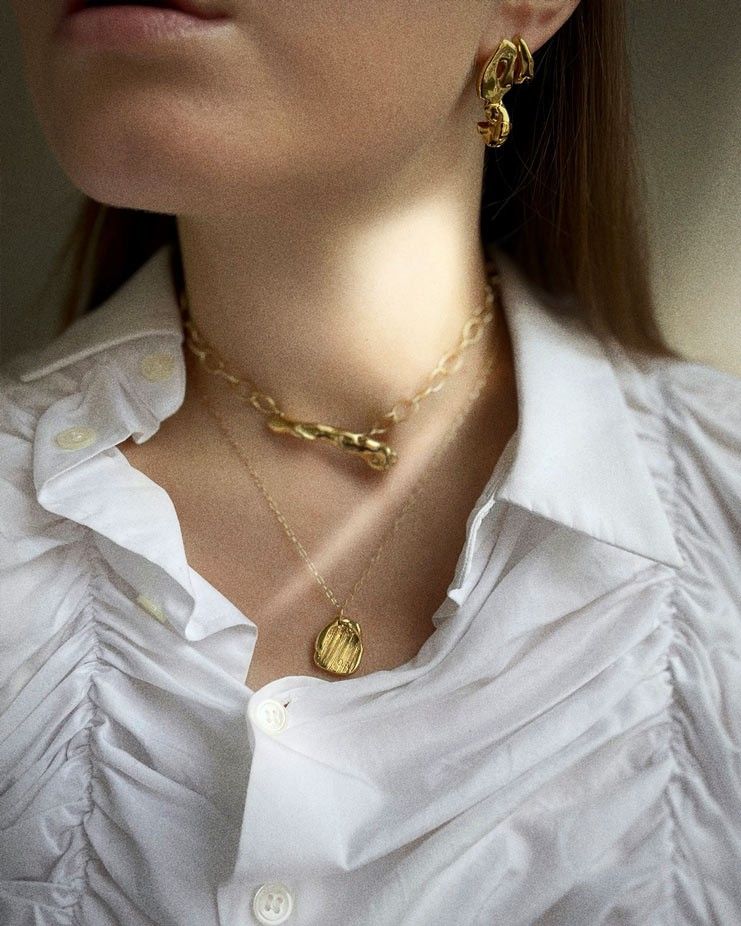 a woman wearing ss necklace and earrings